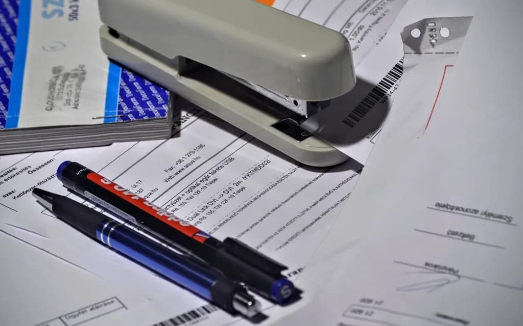 Grampeador, canetas e papéis de escritório sobre a mesa
